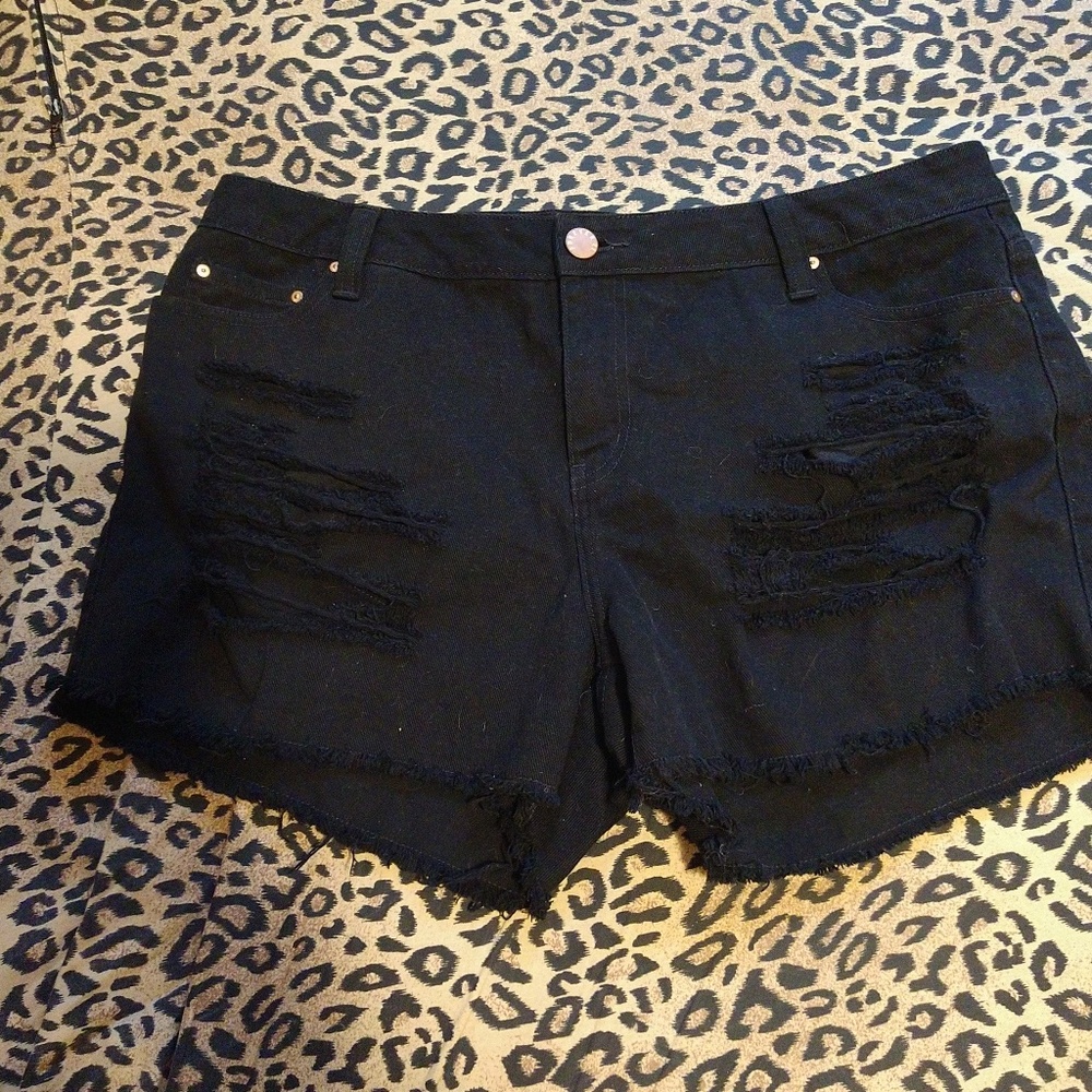 Artfully distressed black jean shorts.